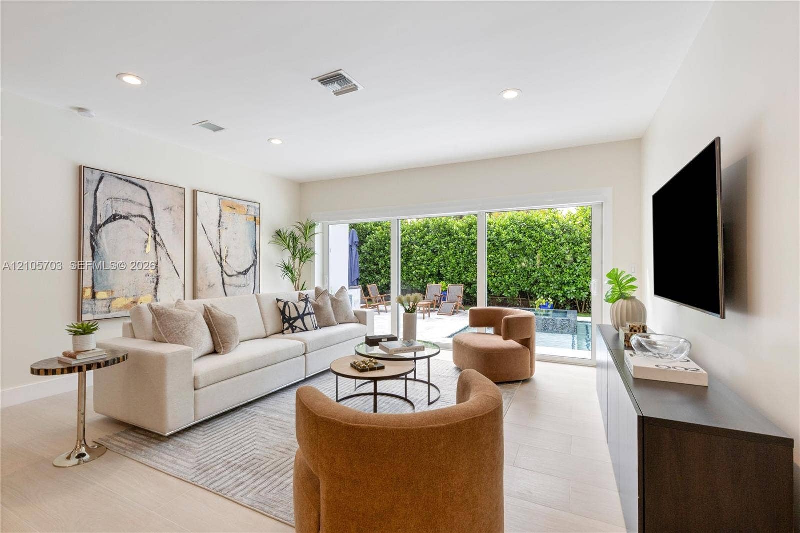 190 NW 102nd Street, Miami Shores, FL 33150 Living space featuring large-format tile flooring, recessed lighting, and full-wall sliding glass doors opening to an exterior patio