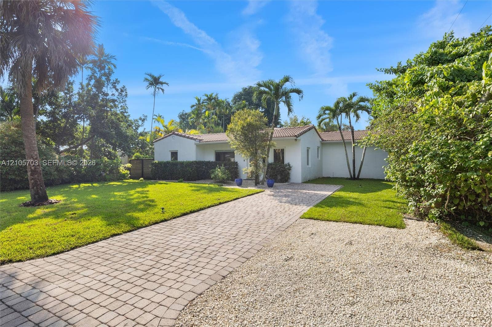 190 NW 102nd Street, Miami Shores, FL 33150 Single-story stucco exterior featuring a terracotta tile roof, paver driveway, and mature landscaping