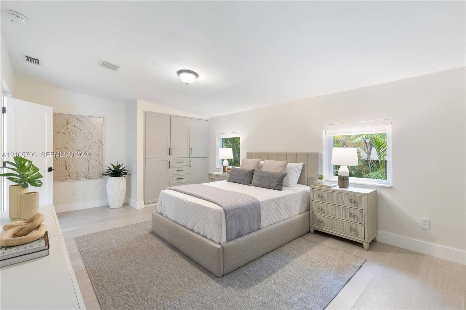 190 NW 102nd Street, Miami Shores, FL 33150 Neutral-toned room featuring light wood-finish flooring, built-in floor-to-ceiling cabinetry, and dual windows