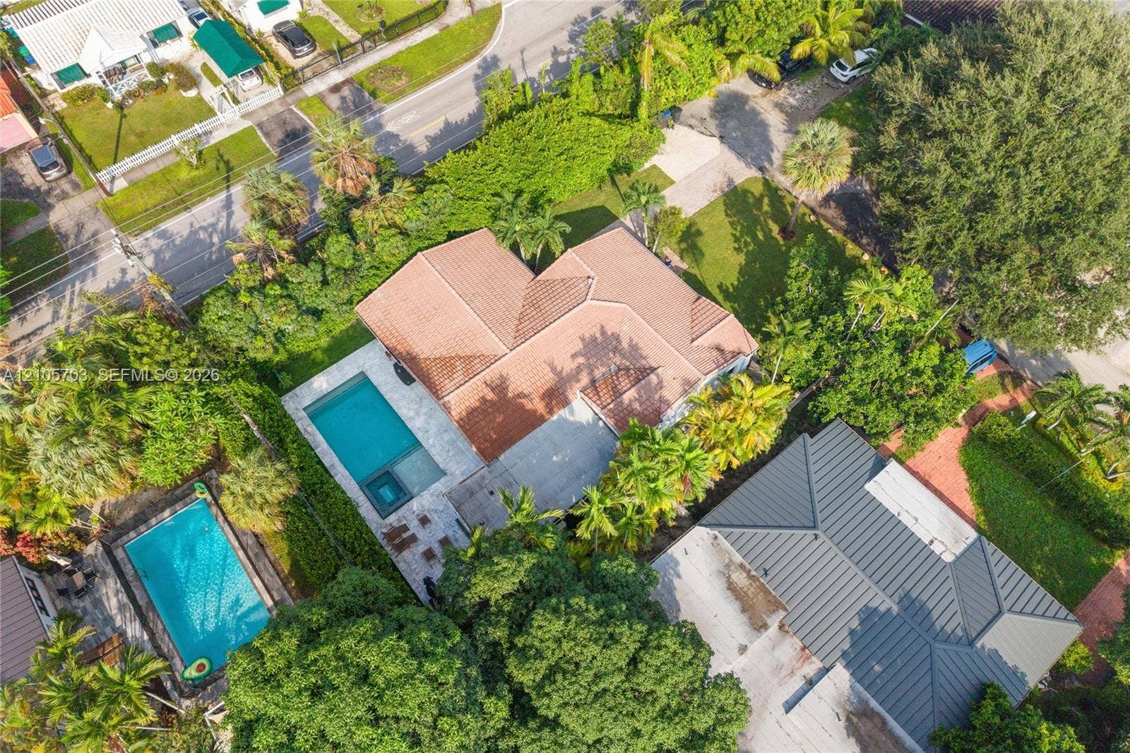 190 NW 102nd Street, Miami Shores, FL 33150 Aerial perspective of property featuring a tile roof, an integrated swimming pool with a spa, and mature landscaping