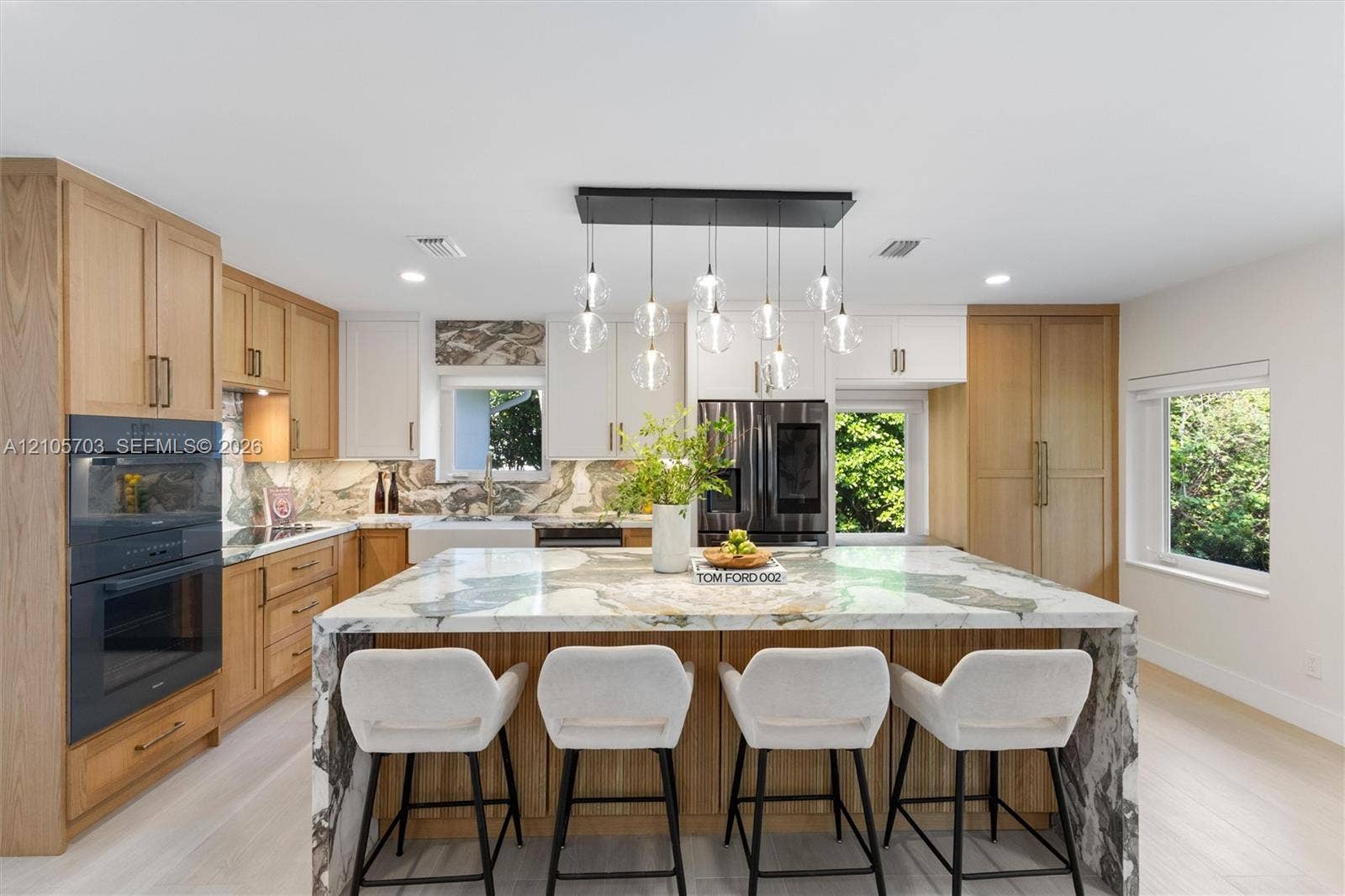 190 NW 102nd Street, Miami Shores, FL 33150 Kitchen featuring custom wood cabinetry, stone-topped waterfall island, built-in double ovens, farmhouse-style sink, and multi-pendant lighting fixture