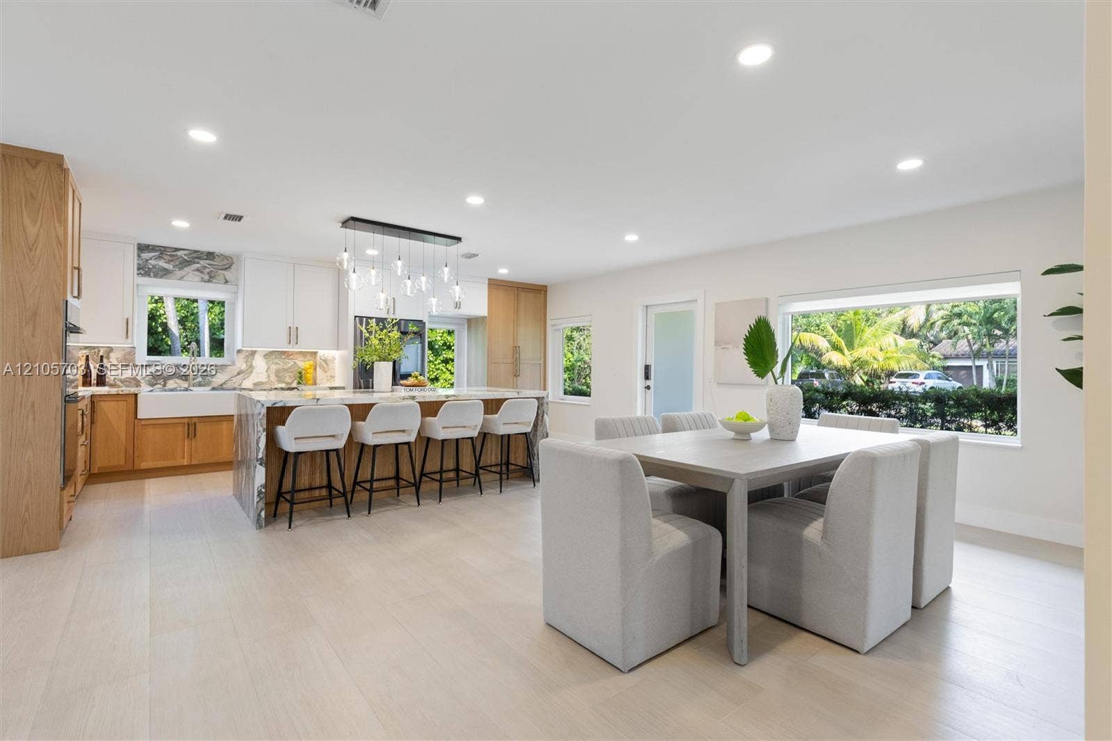 190 NW 102nd Street, Miami Shores, FL 33150 Kitchen featuring wood-finish cabinetry, stone-surface waterfall island with seating, farm-style apron sink, recessed lighting, and large picture windows