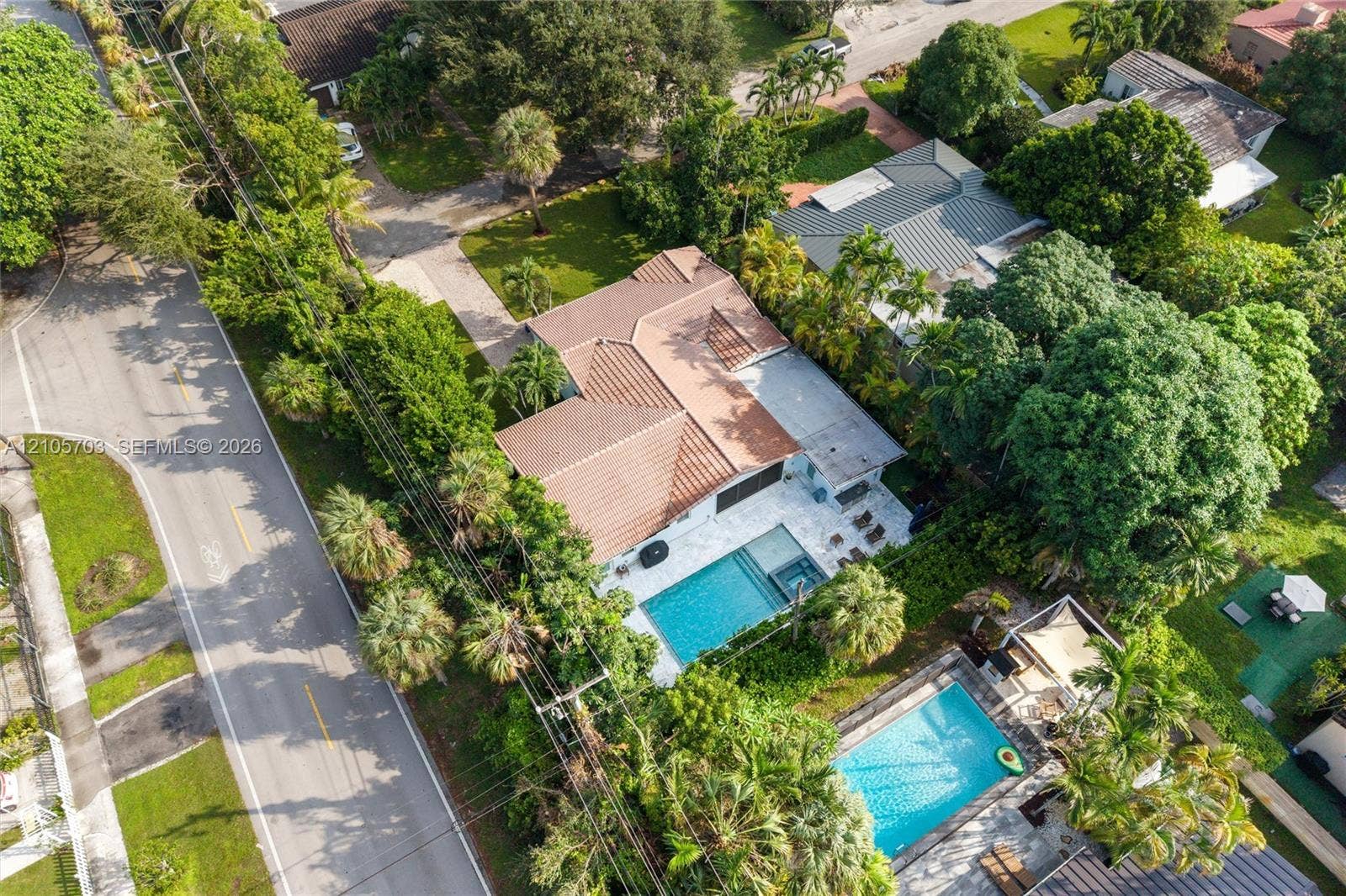 190 NW 102nd Street, Miami Shores, FL 33150 Aerial perspective featuring a tile roof, paved driveway, swimming pool with integrated spa, and mature landscaping