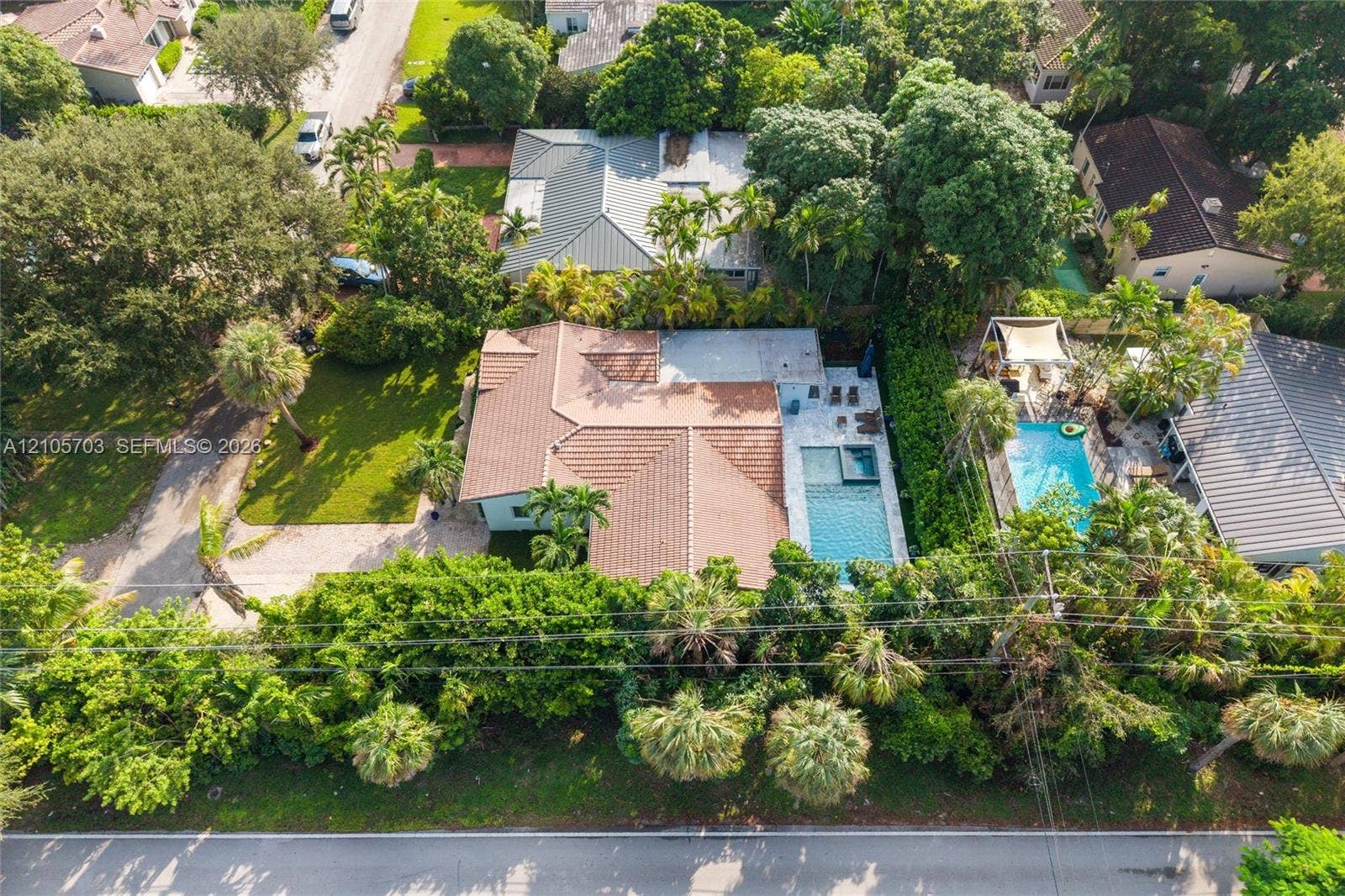 190 NW 102nd Street, Miami Shores, FL 33150 Aerial perspective featuring a tile roof, paved driveway, swimming pool with attached spa, and mature landscaping