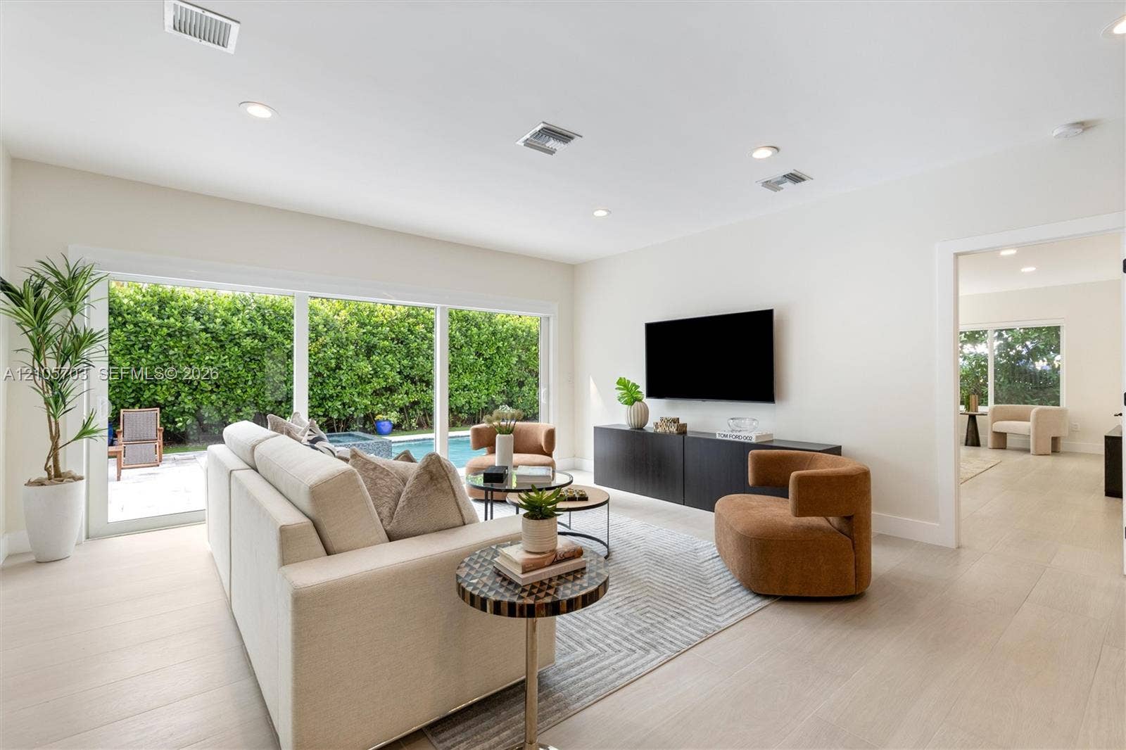 190 NW 102nd Street, Miami Shores, FL 33150 Large sliding glass doors, neutral wood-finish flooring, recessed lighting, and a built-in media console