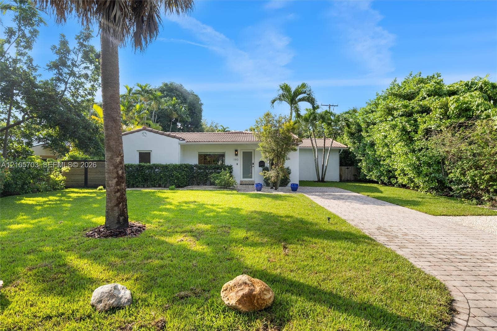 190 NW 102nd Street, Miami Shores, FL 33150 Single-story exterior featuring a light-colored stucco facade, tile roofing, and a paved stone driveway leading to the entrance