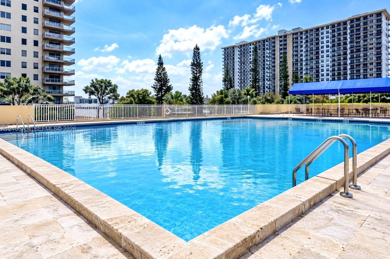 251 174th Street, #212, Sunny Isles Beach, Sunny Isles Beach, FL 33160 Rectangular swimming pool featuring a natural stone deck, metal pool ladders, and a blue canopy structure