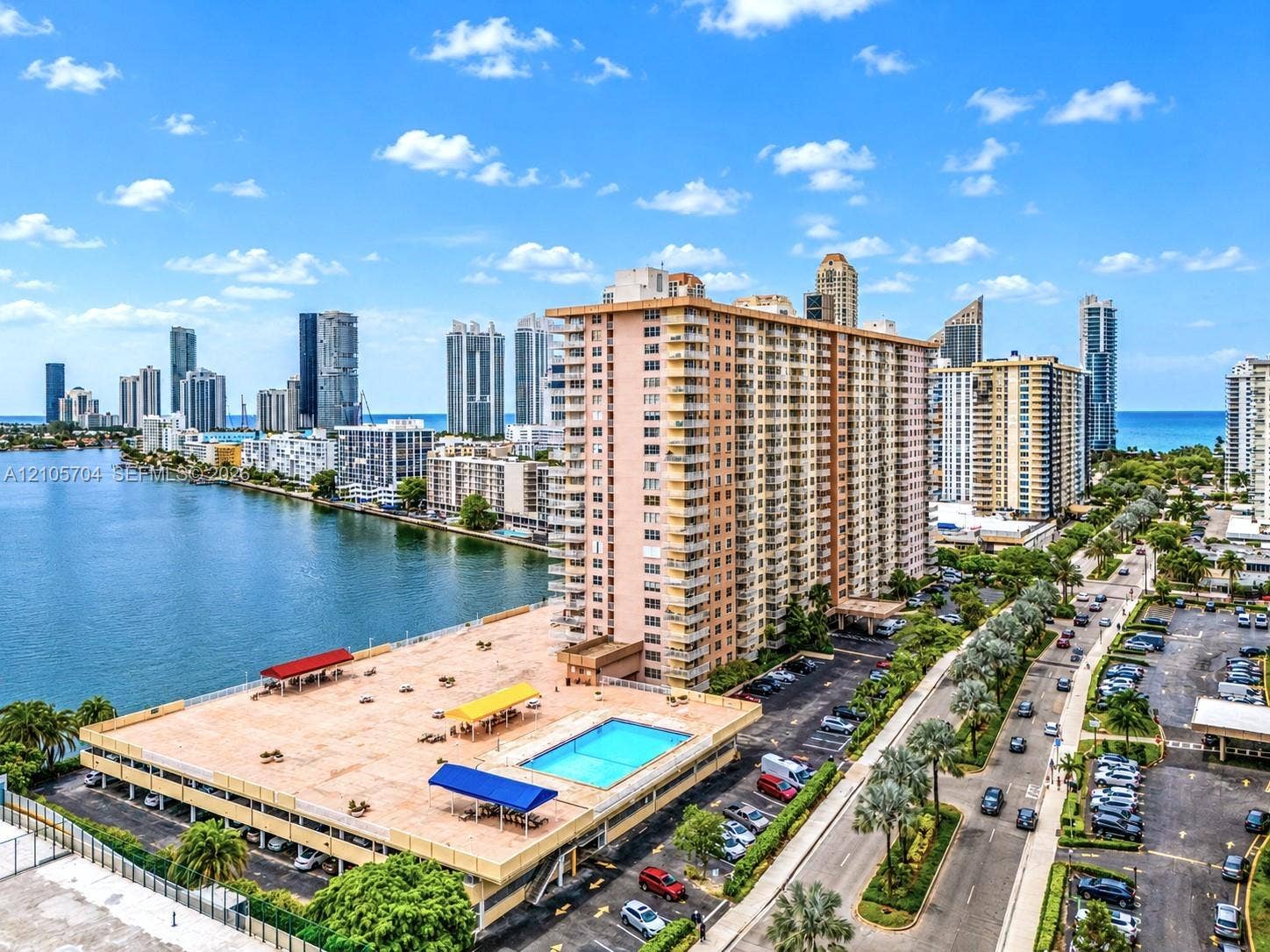 251 174th Street, #212, Sunny Isles Beach, Sunny Isles Beach, FL 33160 High-rise residential building featuring a waterfront location, an elevated outdoor swimming pool, a parking structure, and extensive surrounding cityscape