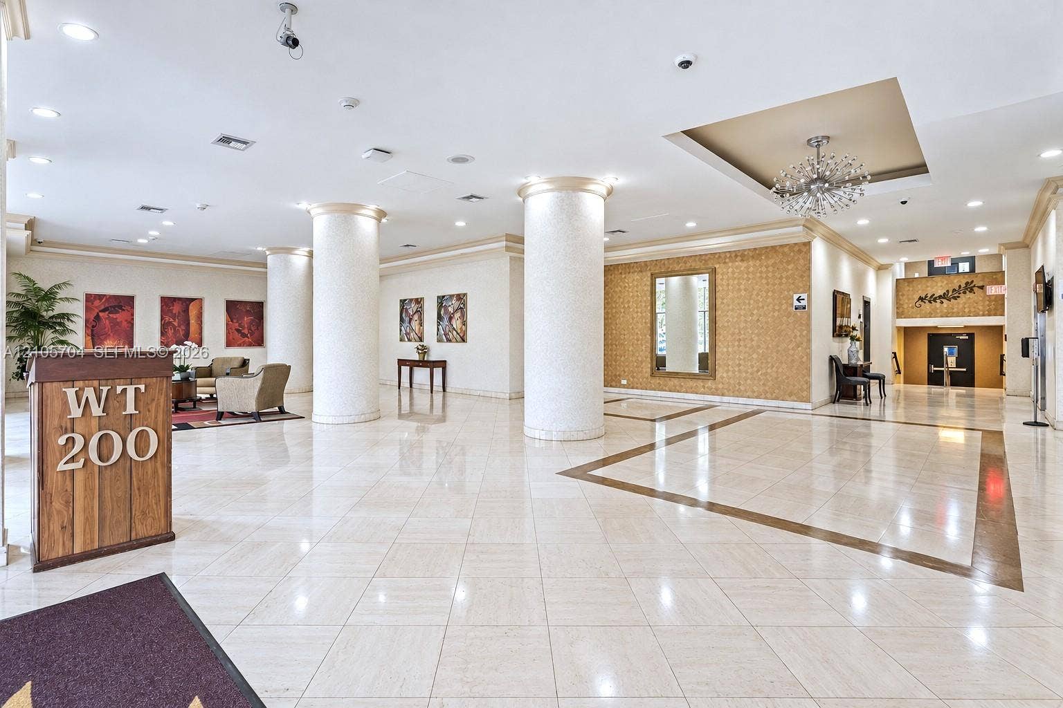 251 174th Street, #212, Sunny Isles Beach, Sunny Isles Beach, FL 33160 Grand lobby featuring polished stone tile flooring with decorative inlay, structural architectural columns, recessed tray ceilings, and a decorative sunburst chandelier
