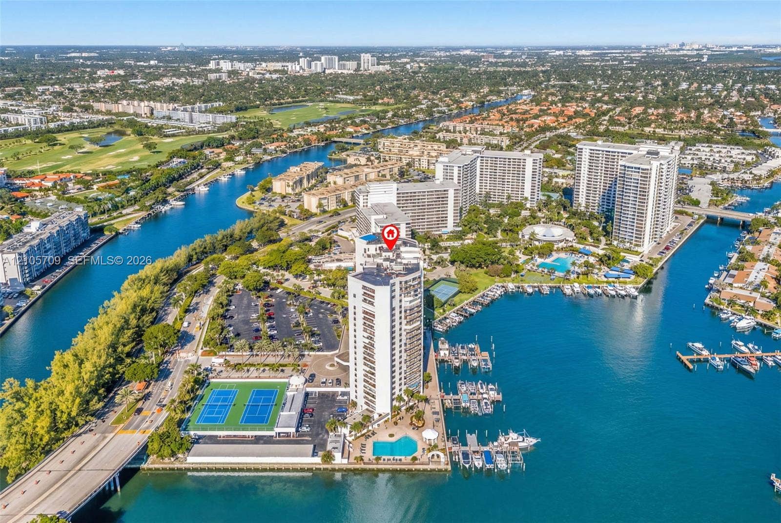 300 Three Islands Boulevard, #516, Hallandale Beach, FL 33009 Aerial view of high-rise building featuring a swimming pool, two tennis courts, and on-site boat slips located on the waterfront