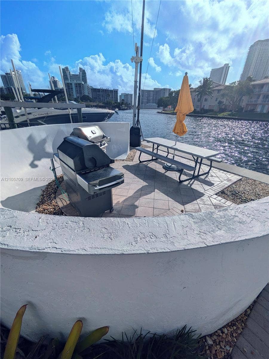 300 Three Islands Boulevard, #516, Hallandale Beach, FL 33009 Waterfront patio featuring a curved masonry wall, tile pavers, and direct bulkhead access