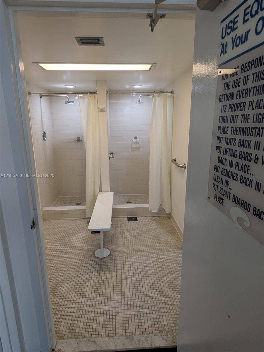 300 Three Islands Boulevard, #516, Hallandale Beach, FL 33009 Dual shower stalls featuring tile surround, mosaic floor tiling, wall-mounted metal grab bars, and recessed lighting