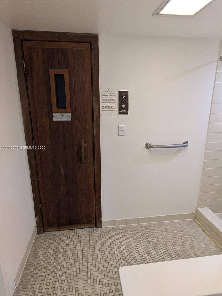 300 Three Islands Boulevard, #516, Hallandale Beach, FL 33009 Sauna featuring a wood door with a vertical glass insert, wall-mounted control panel, and tiled flooring
