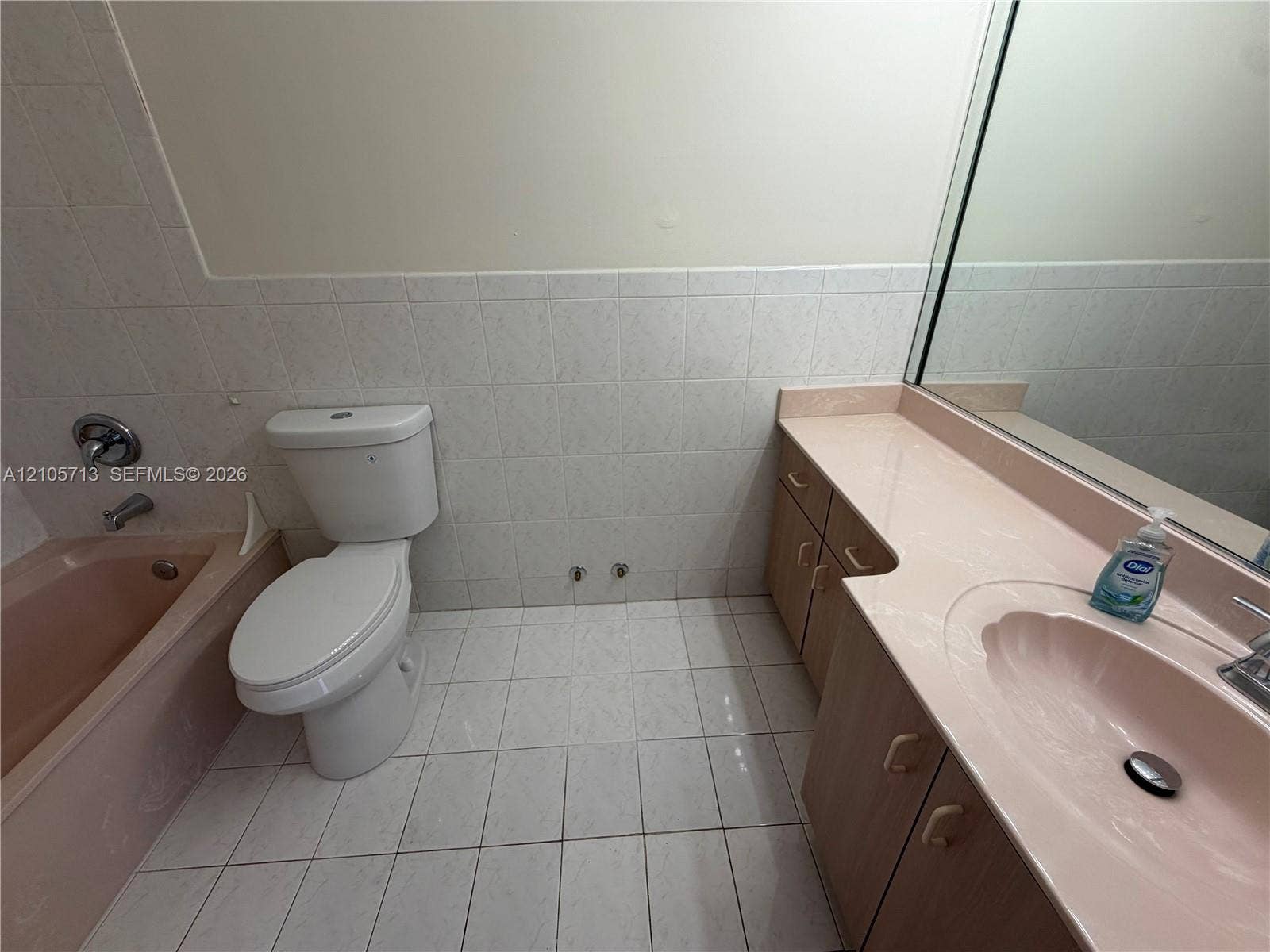 Integrated vanity with a molded basin, white wall tile, tub surround, and full-width vanity mirror