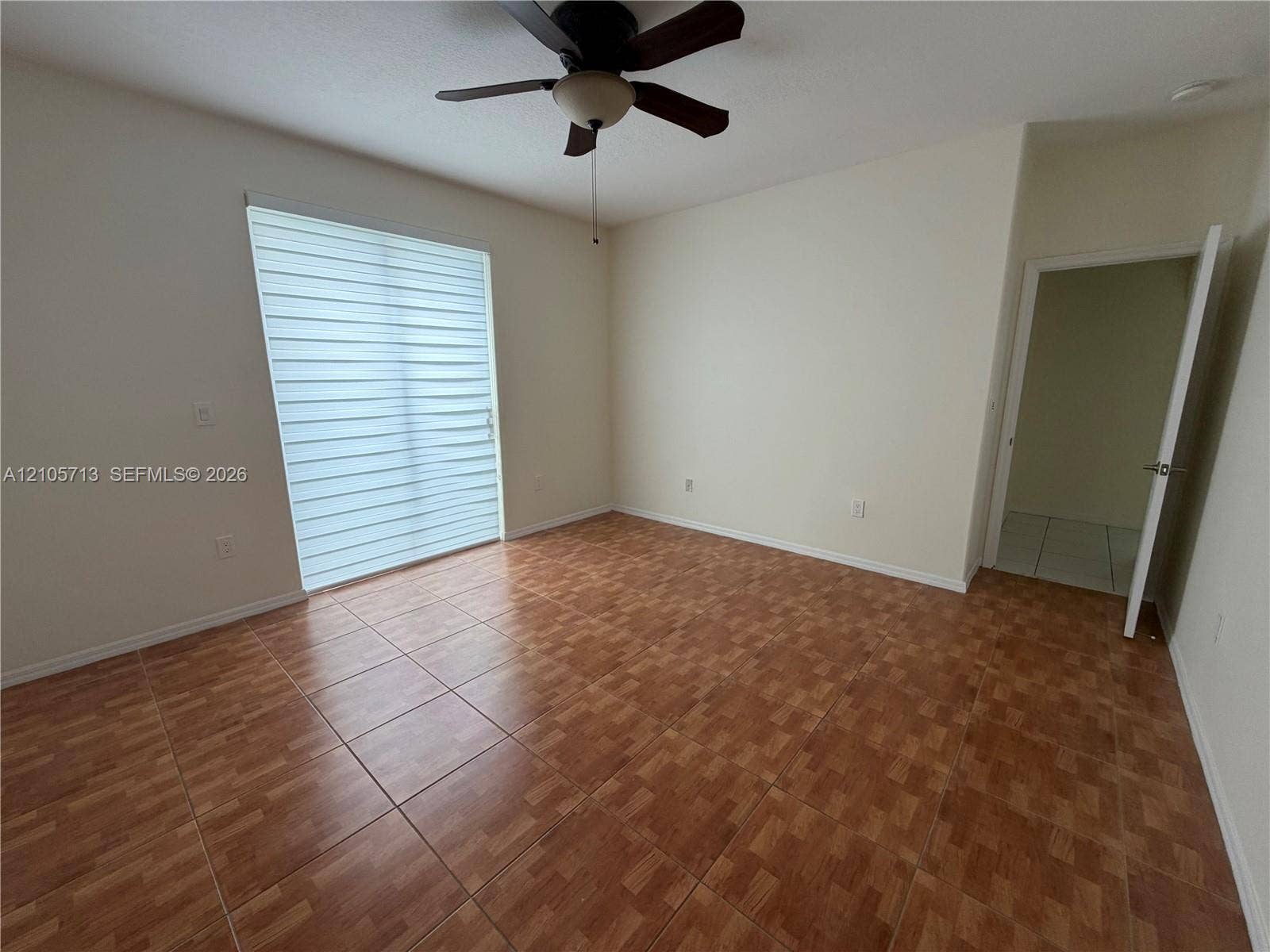 Interior space featuring ceramic tile flooring, a multi-blade ceiling fan, and a sliding glass door with integrated window shades