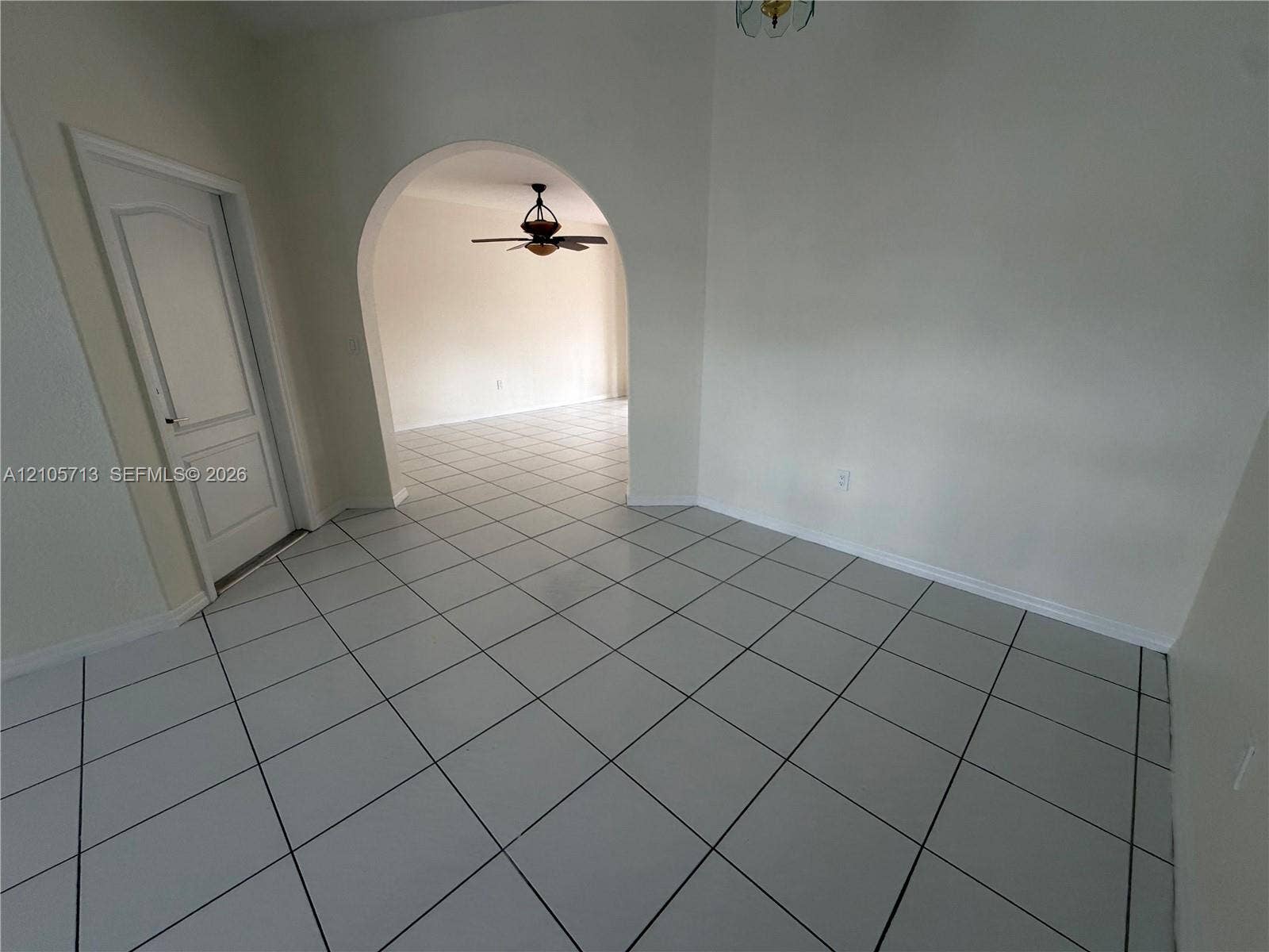 Ceramic tile flooring, arched entryway, and six-panel interior door