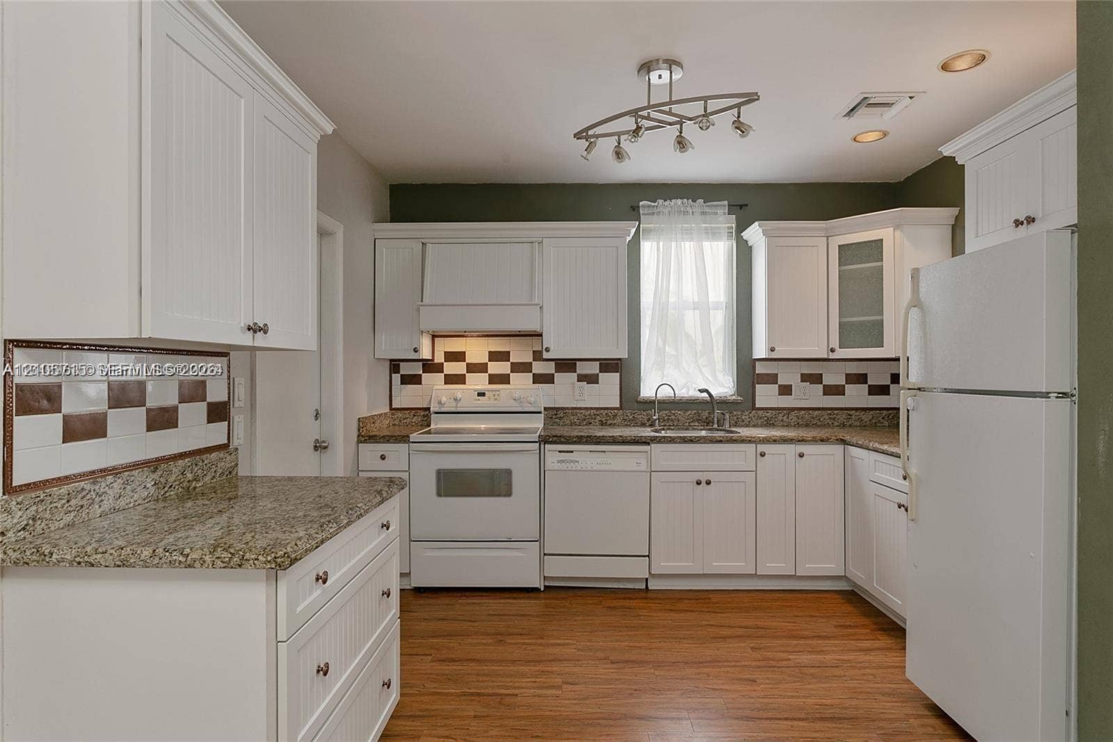 10524 NW 57th Court, Coral Springs, FL 33076 Kitchen featuring white cabinetry, stone-finish countertops, geometric tile backsplash, wood-finish flooring, and integrated lighting fixtures