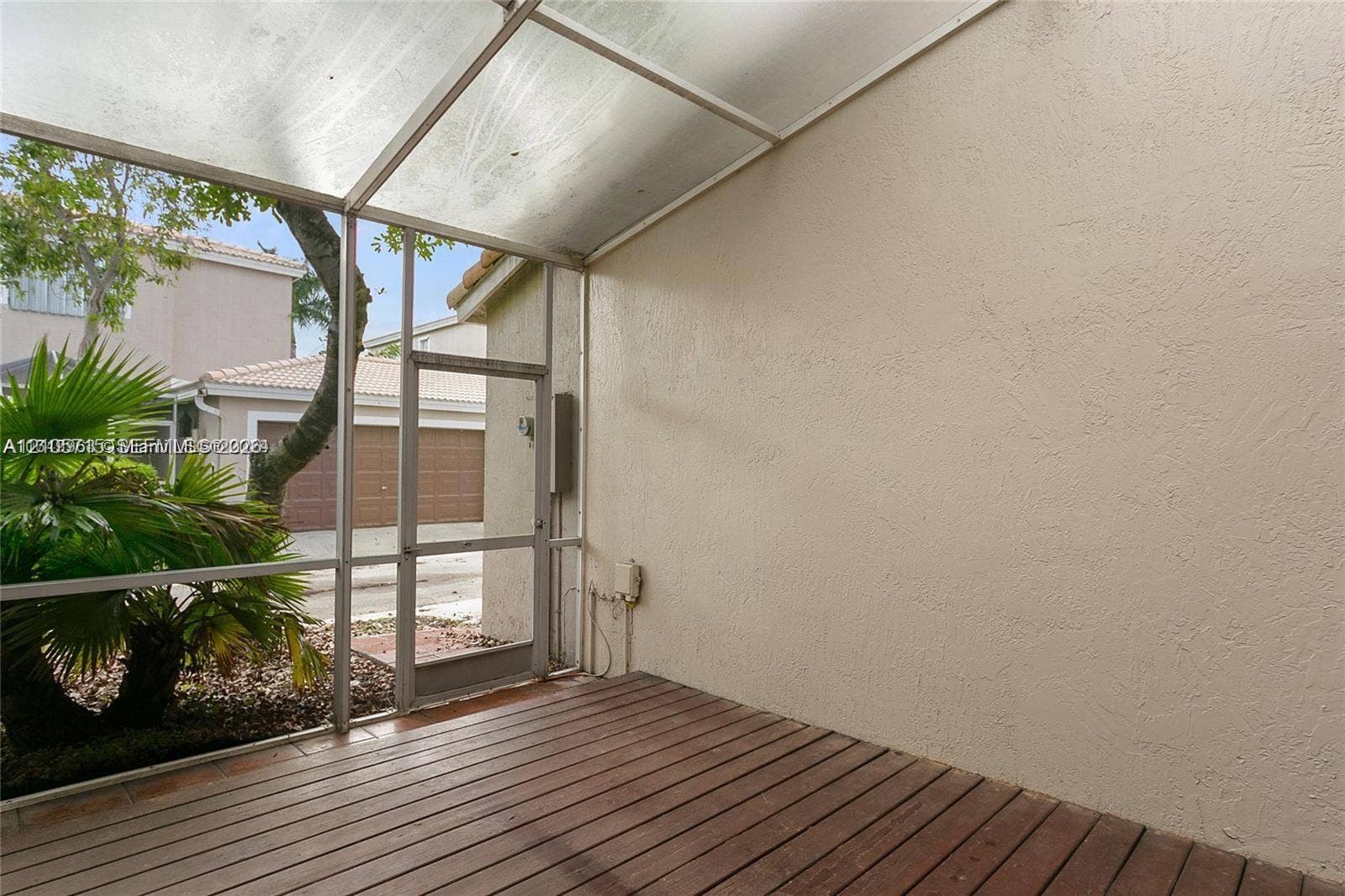 10524 NW 57th Court, Coral Springs, FL 33076 Screened patio featuring wood-finish flooring, a translucent roof panel, and stucco walls