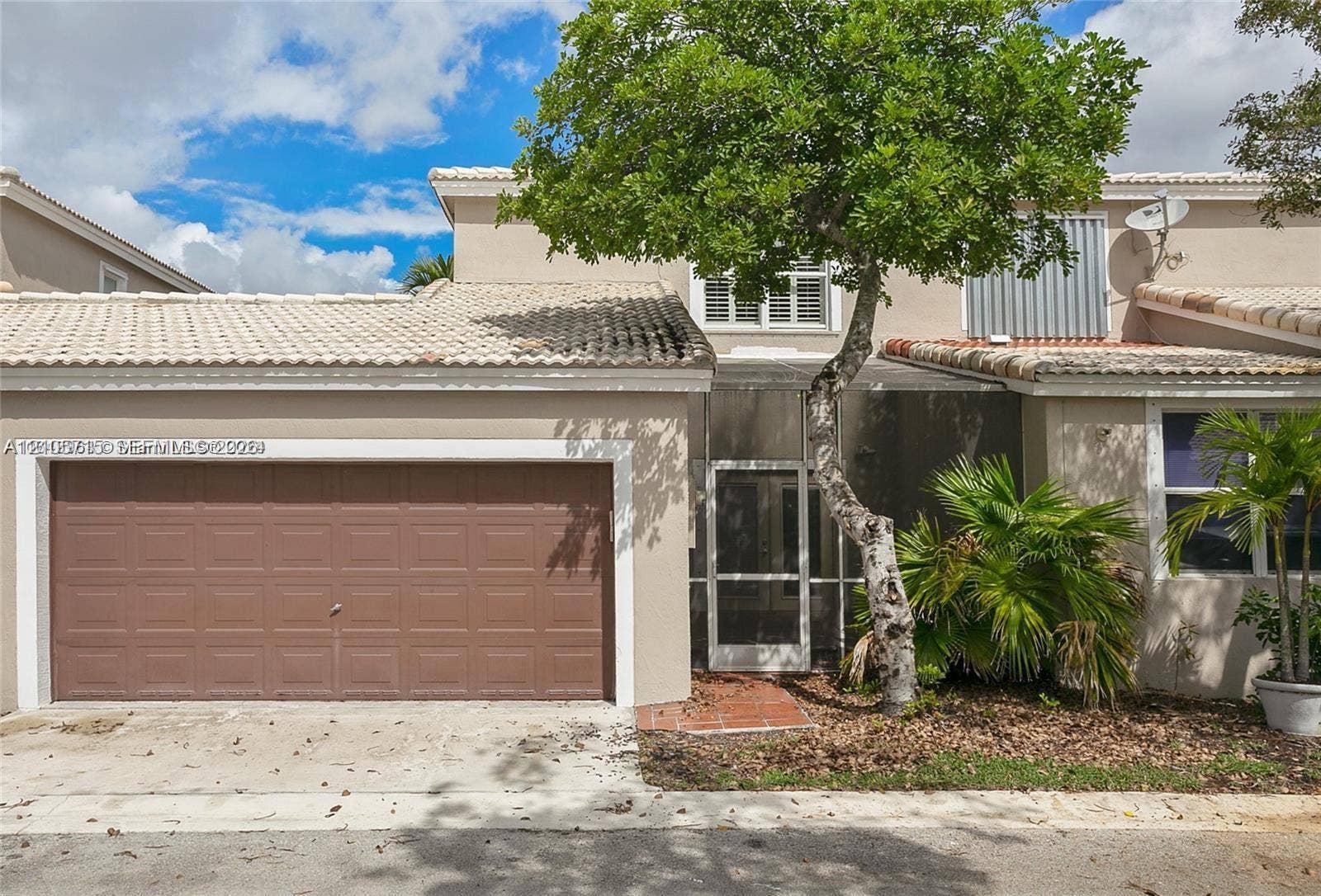 10524 NW 57th Court, Coral Springs, FL 33076 Stucco exterior featuring a tiled roof, attached garage with sectional door, and screened entry