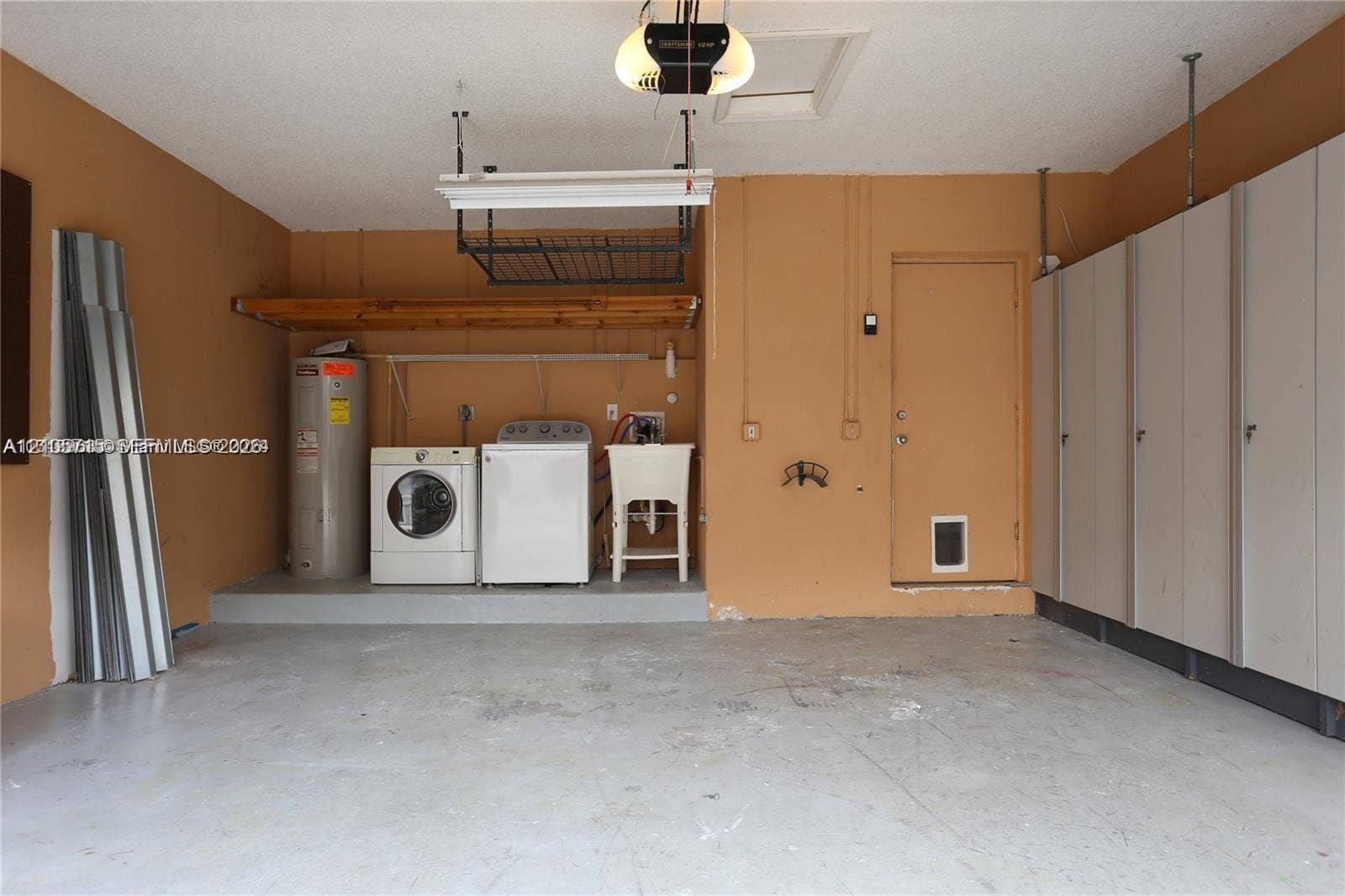 10524 NW 57th Court, Coral Springs, FL 33076 Garage space featuring built-in floor-to-ceiling cabinetry, overhead ceiling storage rack, utility sink, and wall-mounted shelving