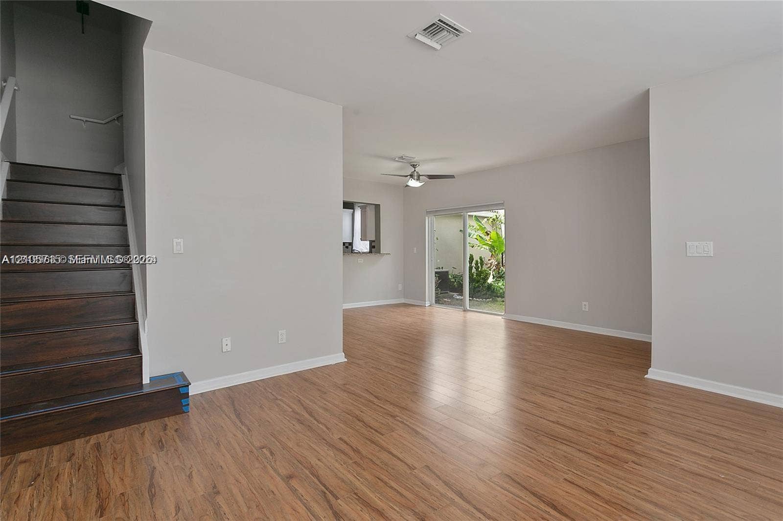 10524 NW 57th Court, Coral Springs, FL 33076 Open interior featuring wood-finish flooring, a staircase with dark wood-finish treads, a neutral wall palette, a ceiling-mounted fan, and glass sliding doors