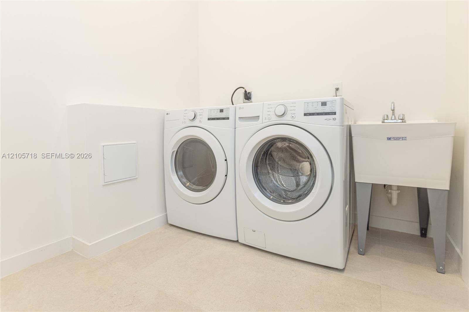 2200 Brickell Avenue, #GV16, Miami, FL 33129 Utility area featuring a deep-basin laundry sink with a dual-handle faucet and dedicated washer and dryer connections