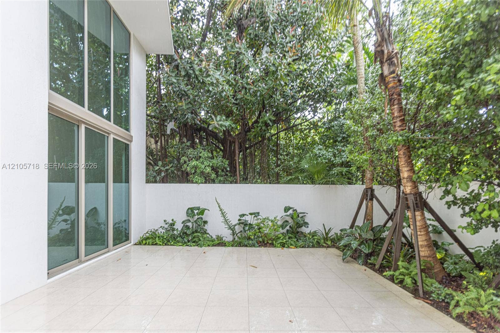 2200 Brickell Avenue, #GV16, Miami, FL 33129 Patio featuring oversized light-toned tile flooring, floor-to-ceiling windows, white perimeter wall, and established perimeter landscaping