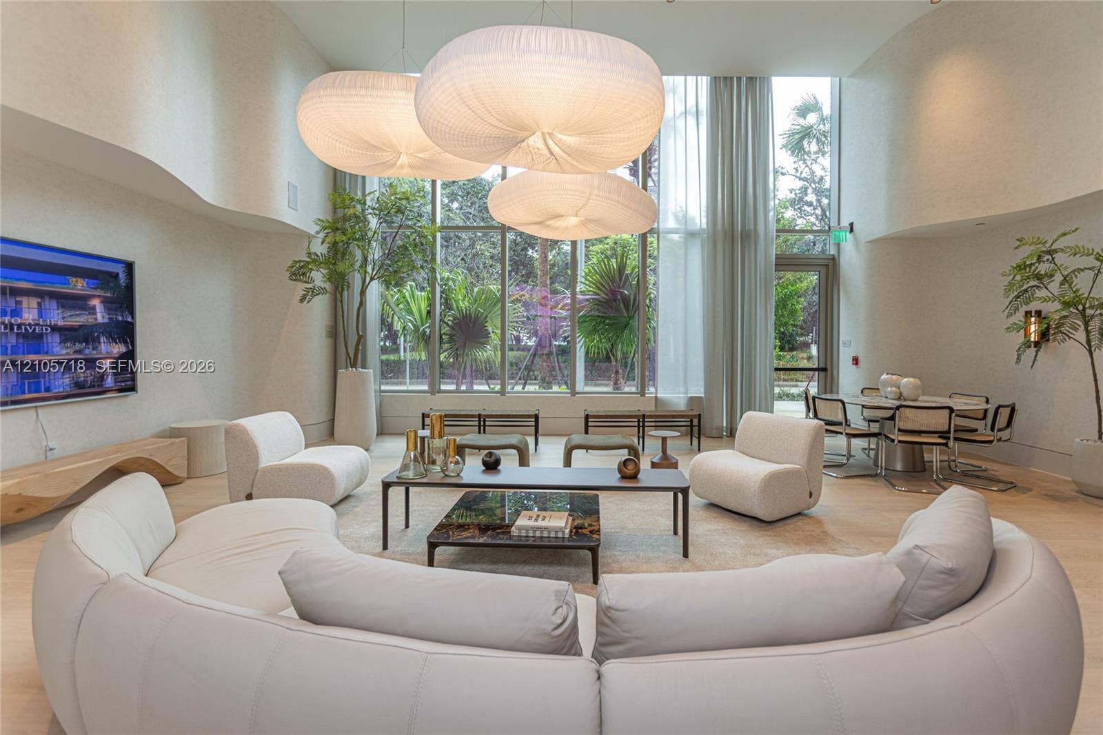 2200 Brickell Avenue, #GV16, Miami, FL 33129 Double-height ceilings, floor-to-ceiling windows, sculptural fabric pendant lighting, curved wall architecture, and light-toned flooring