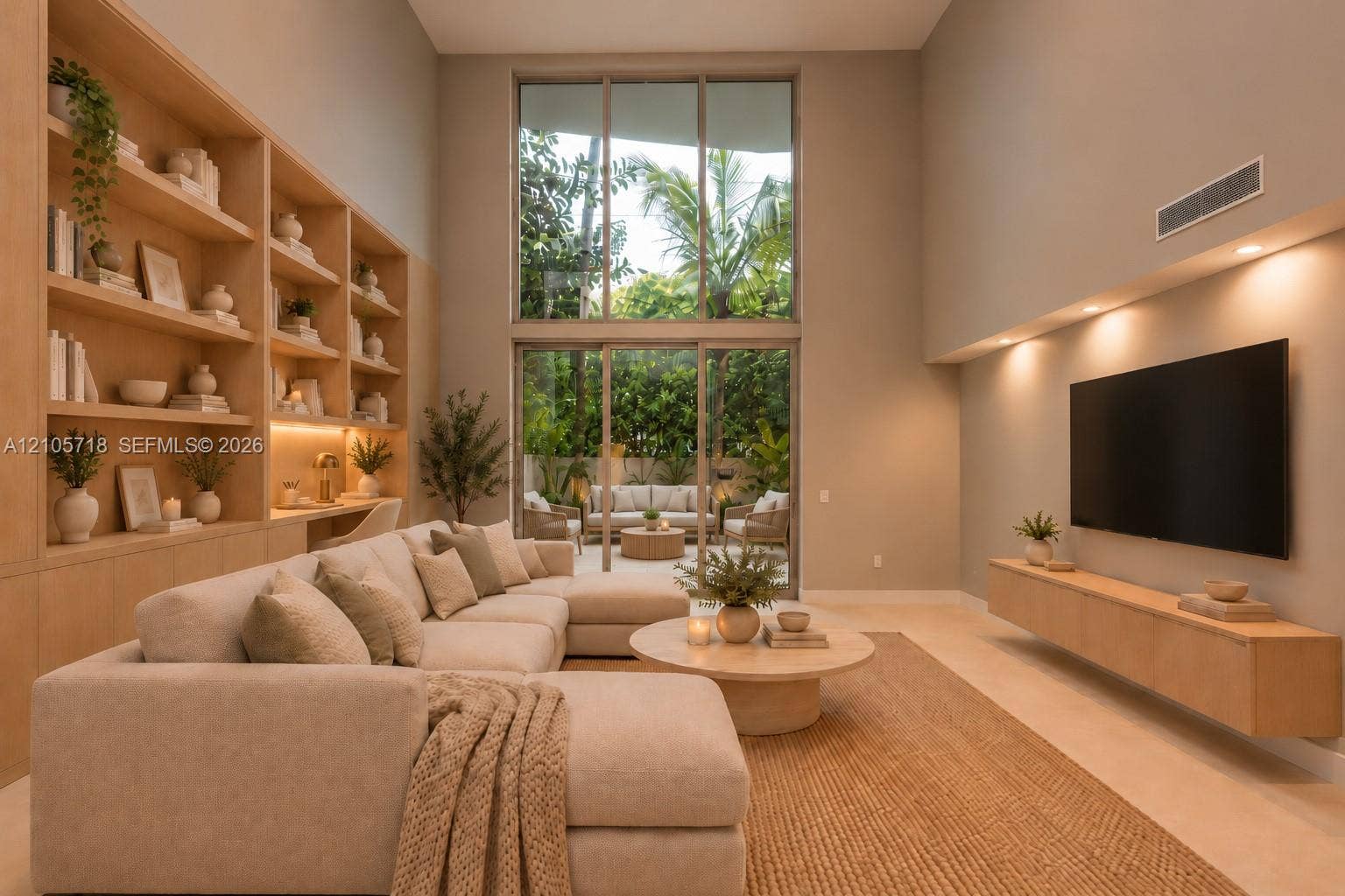 2200 Brickell Avenue, #GV16, Miami, FL 33129 Double-height ceiling featuring expansive floor-to-ceiling windows, custom built-in light-tone wood shelving with integrated task lighting, and a wall-mounted floating media console