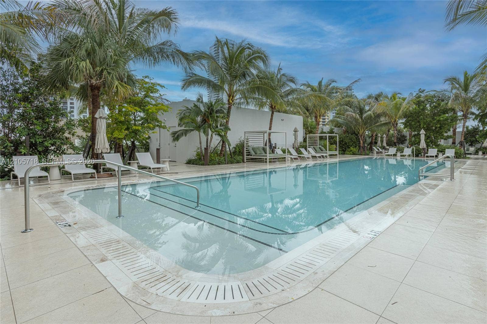 2200 Brickell Avenue, #GV16, Miami, FL 33129 Rectangular swimming pool featuring a light-toned stone deck, integrated tiered steps, a stainless steel handrail, and mature palm tree landscaping