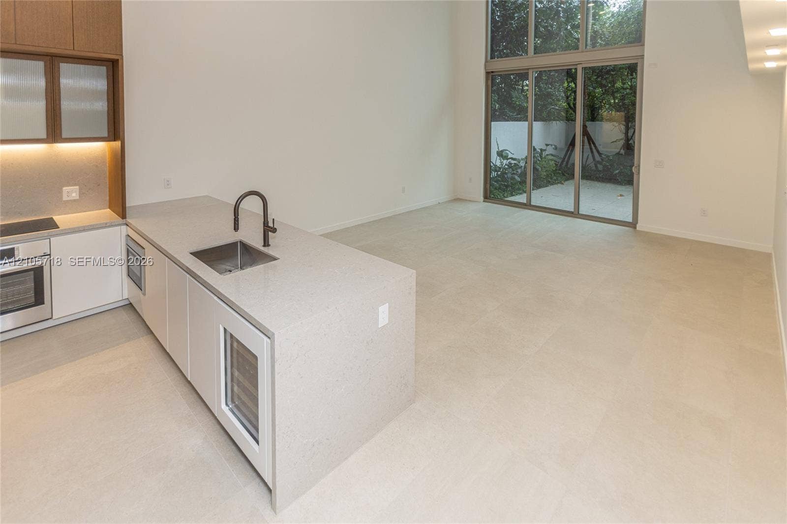 2200 Brickell Avenue, #GV16, Miami, FL 33129 Kitchen featuring a stone-surface island, built-in wine refrigeration, high-ceiling glass sliding doors, and large-format tile flooring
