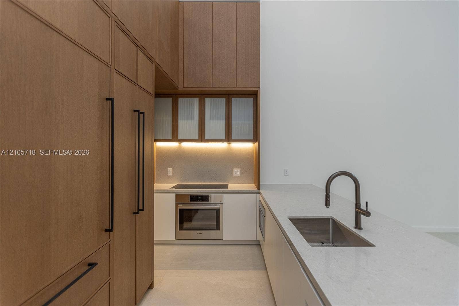 2200 Brickell Avenue, #GV16, Miami, FL 33129 Kitchen featuring full-height wood-finish cabinetry, white solid surface countertops, a stainless steel wall oven, an integrated cooktop, and an undermount sink with a high-arch pull-down faucet