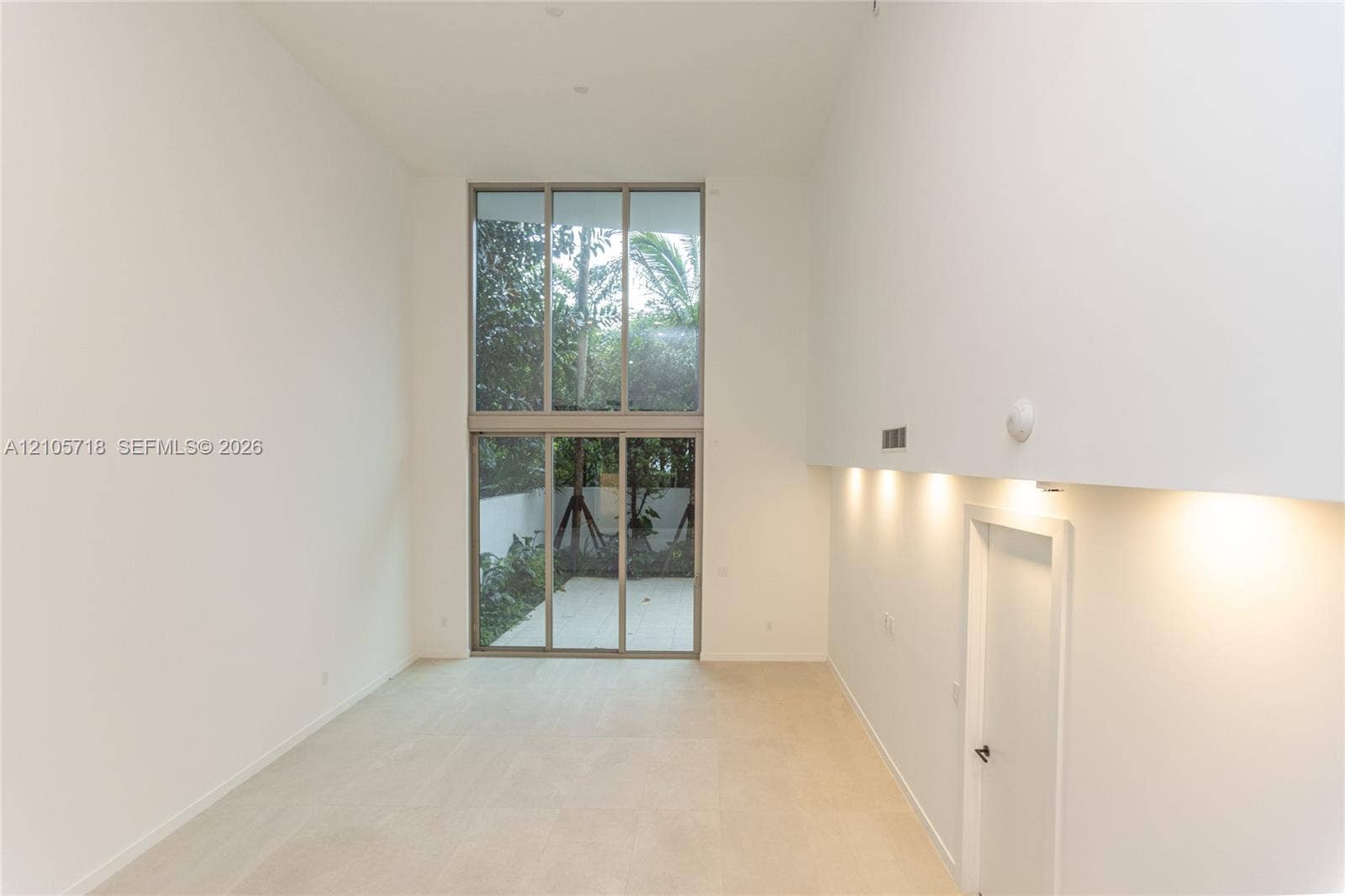 2200 Brickell Avenue, #GV16, Miami, FL 33129 Double-height ceilings, expansive floor-to-ceiling windows, light-toned stone flooring, and integrated recessed wall lighting
