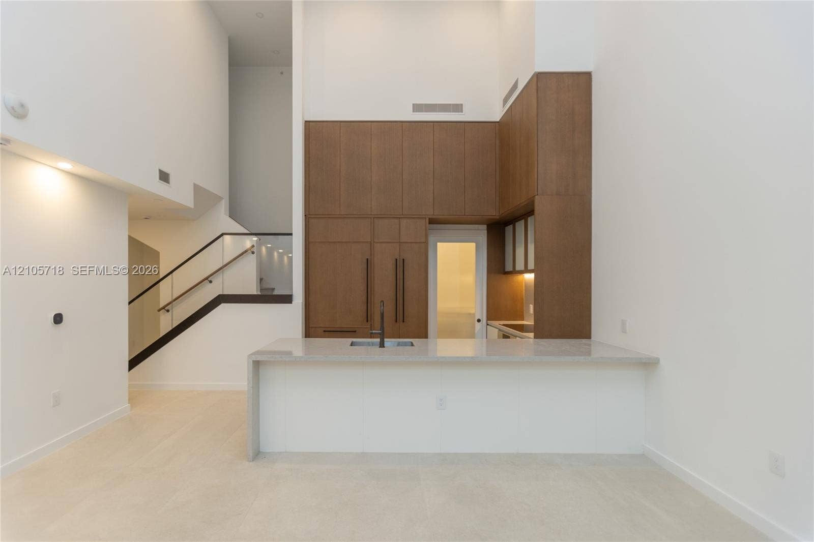 2200 Brickell Avenue, #GV16, Miami, FL 33129 Kitchen featuring floor-to-ceiling wood-finish cabinetry, stone-surfaced waterfall island with integrated sink, and matte black hardware