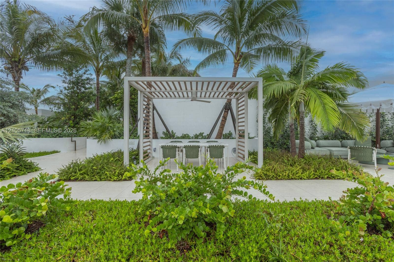 2200 Brickell Avenue, #GV16, Miami, FL 33129 Outdoor patio featuring a white slatted pergola, integrated ceiling fan, light-colored paver flooring, raised garden beds, and mature palm trees