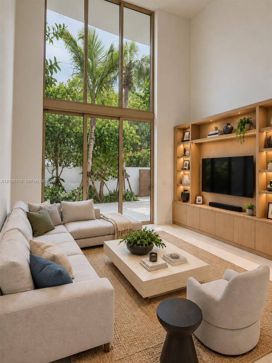 2200 Brickell Avenue, #GV16, Miami, FL 33129 Double-height ceiling featuring floor-to-ceiling windows, custom built-in wood cabinetry with integrated lighting, and neutral stone flooring