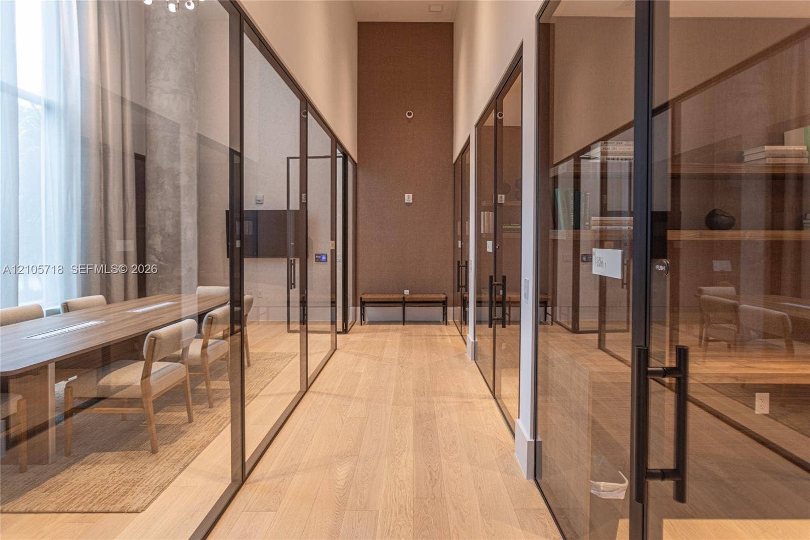 2200 Brickell Avenue, #GV16, Miami, FL 33129 Hallway featuring full-height glass partitions with matte black framing, wood-finish flooring, high ceilings, and built-in shelving