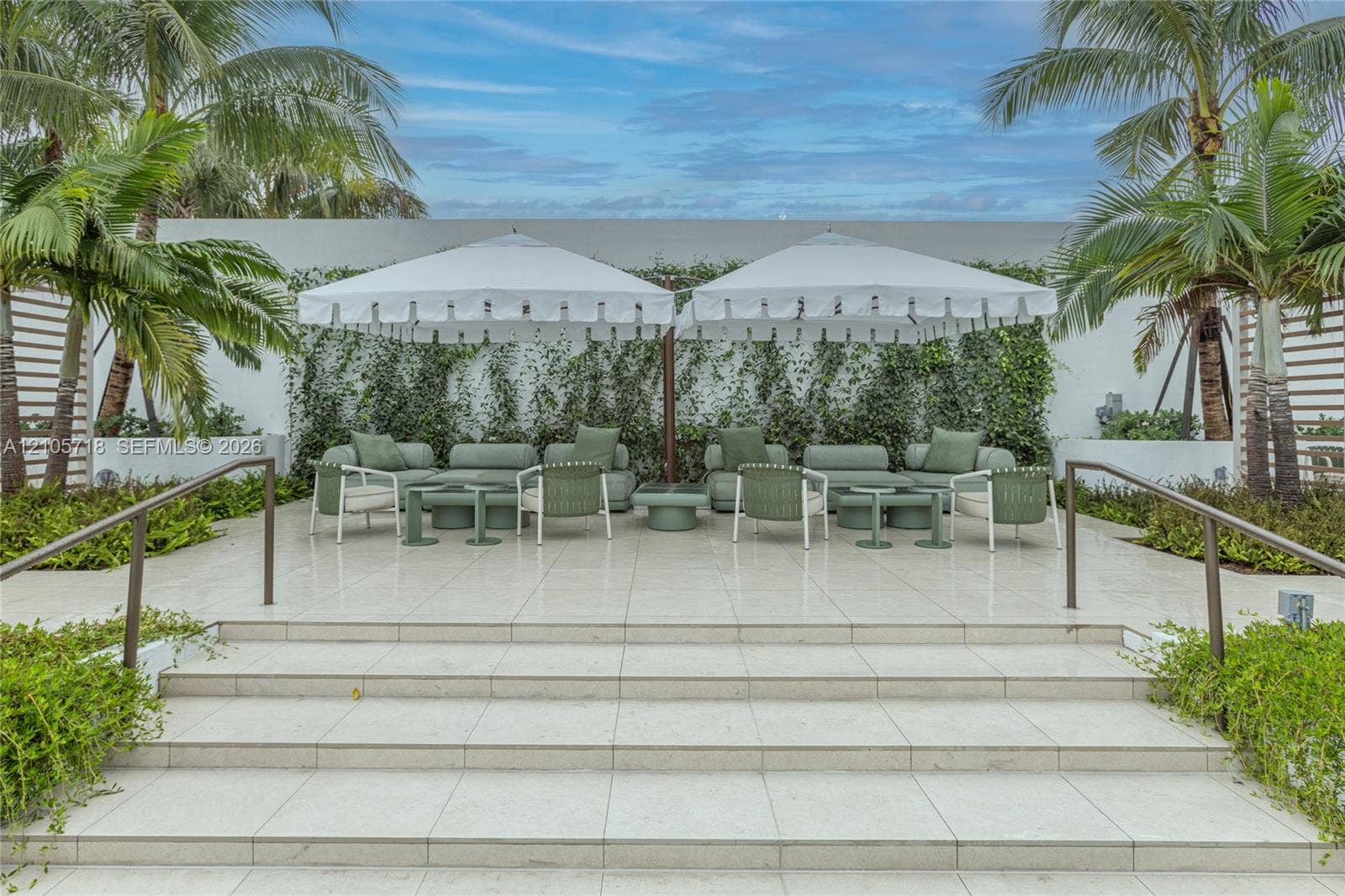 2200 Brickell Avenue, #GV16, Miami, FL 33129 Outdoor terrace featuring oversized light-colored tiling, a tiered staircase with metal handrails, a climbing vine wall, and perimeter tropical landscaping