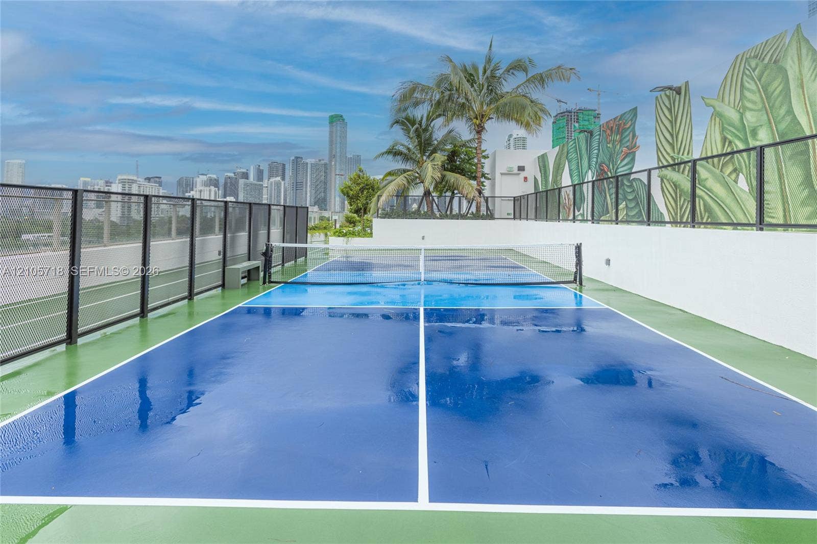 2200 Brickell Avenue, #GV16, Miami, FL 33129 Rooftop pickleball court featuring a high-contrast blue and green acrylic surface, integrated netting, perimeter metal fencing, and decorative wall mural