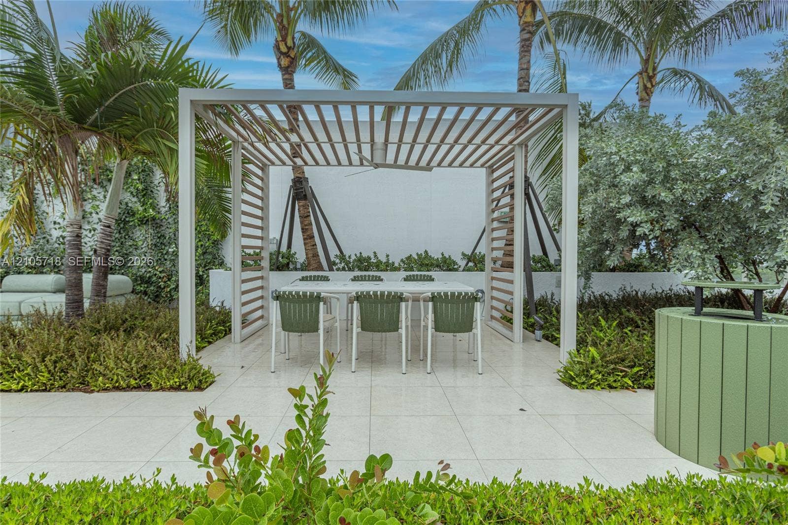 2200 Brickell Avenue, #GV16, Miami, FL 33129 Outdoor patio featuring white tile flooring, a structured wooden pergola with an integrated ceiling fan, and surrounding tropical landscaping