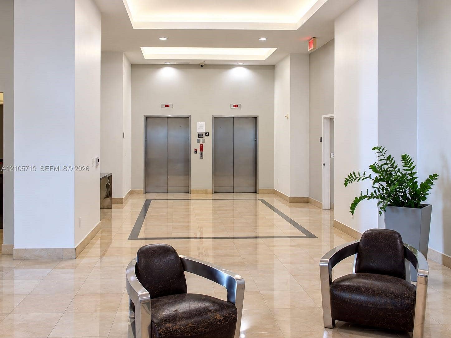 1 Glen Royal Parkway, #1510, Miami, FL 33125 Lobby featuring polished stone flooring with a central inlay border, dual stainless steel elevator doors, and recessed tray ceiling lighting