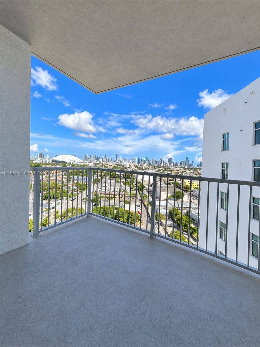 1 Glen Royal Parkway, #1510, Miami, FL 33125 Covered balcony featuring concrete flooring and a metal railing, overlooking an urban skyline