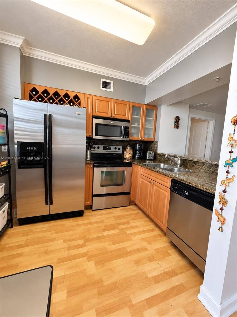 1 Glen Royal Parkway, #1510, Miami, FL 33125 Kitchen featuring wood cabinetry with integrated wine storage, stainless steel appliances, stone countertops, double-basin sink, and wood-finish flooring