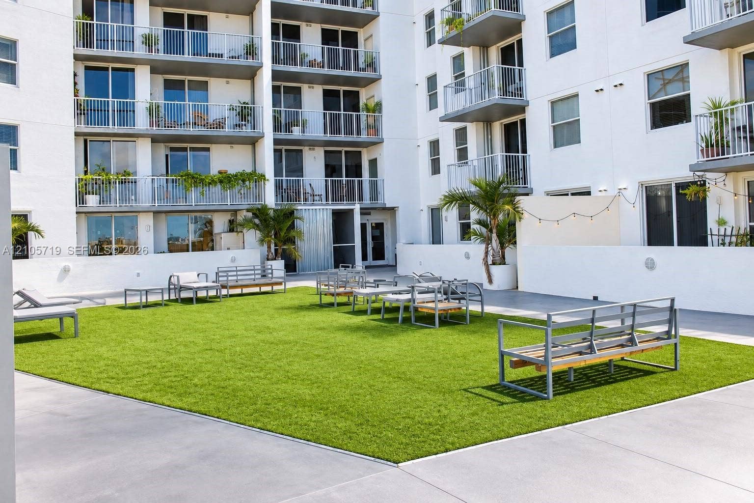 1 Glen Royal Parkway, #1510, Miami, FL 33125 Outdoor courtyard featuring a manicured lawn, smooth concrete perimeter, perimeter wall lighting, and established palm trees