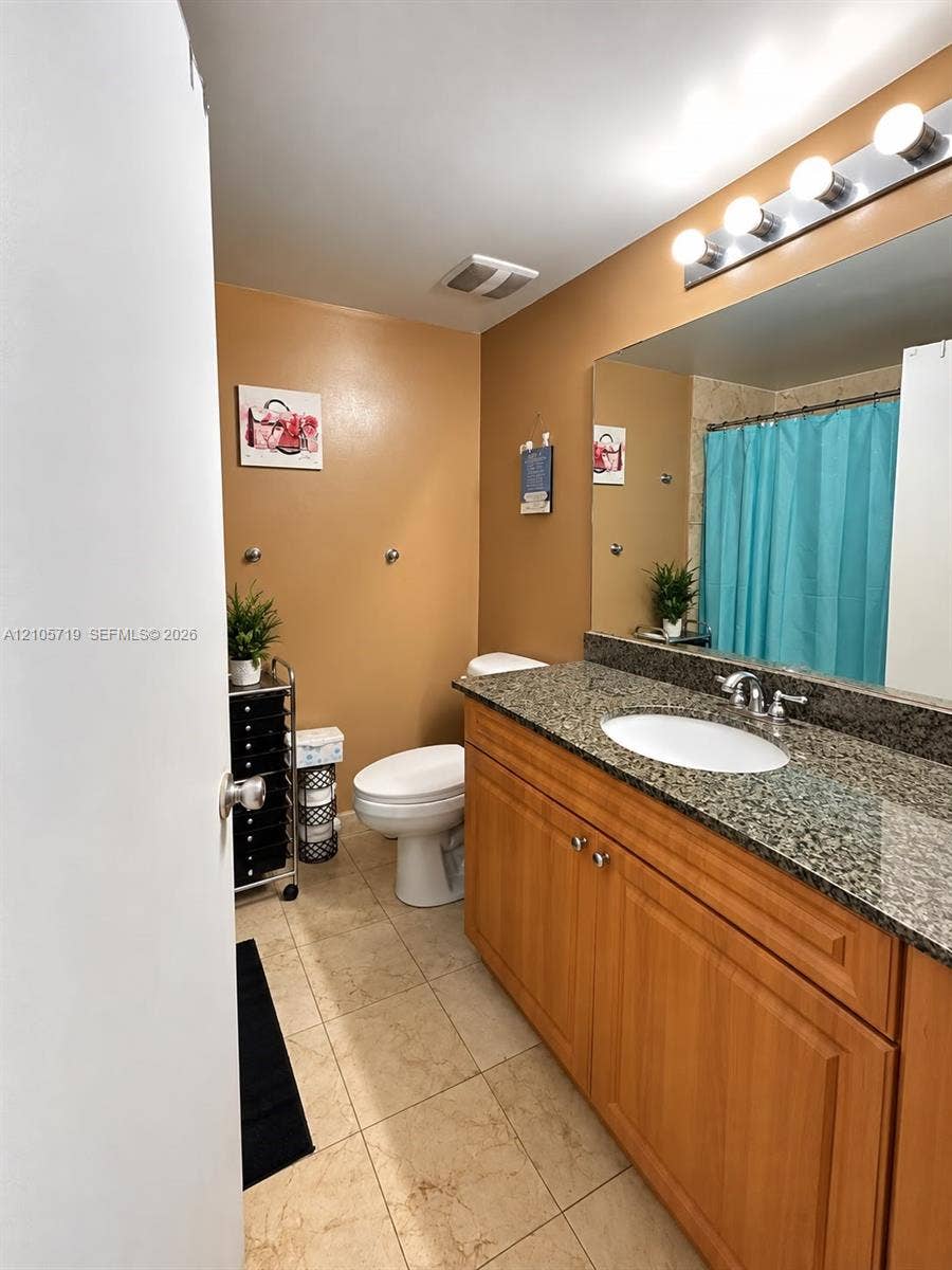 1 Glen Royal Parkway, #1510, Miami, FL 33125 Bathroom featuring a wood-finish vanity with an integrated stone-patterned countertop, oval undermount sink, full-width wall mirror, and tiled flooring
