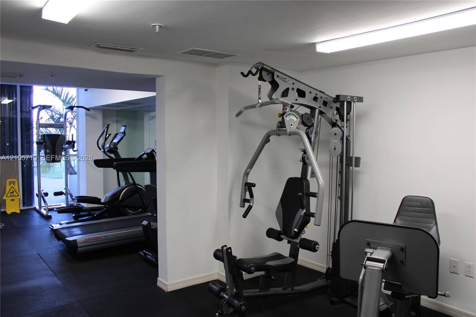 1 Glen Royal Parkway, #1510, Miami, FL 33125 Fitness area featuring resilient rubber flooring, expansive wall-to-wall mirrors, and overhead fluorescent lighting