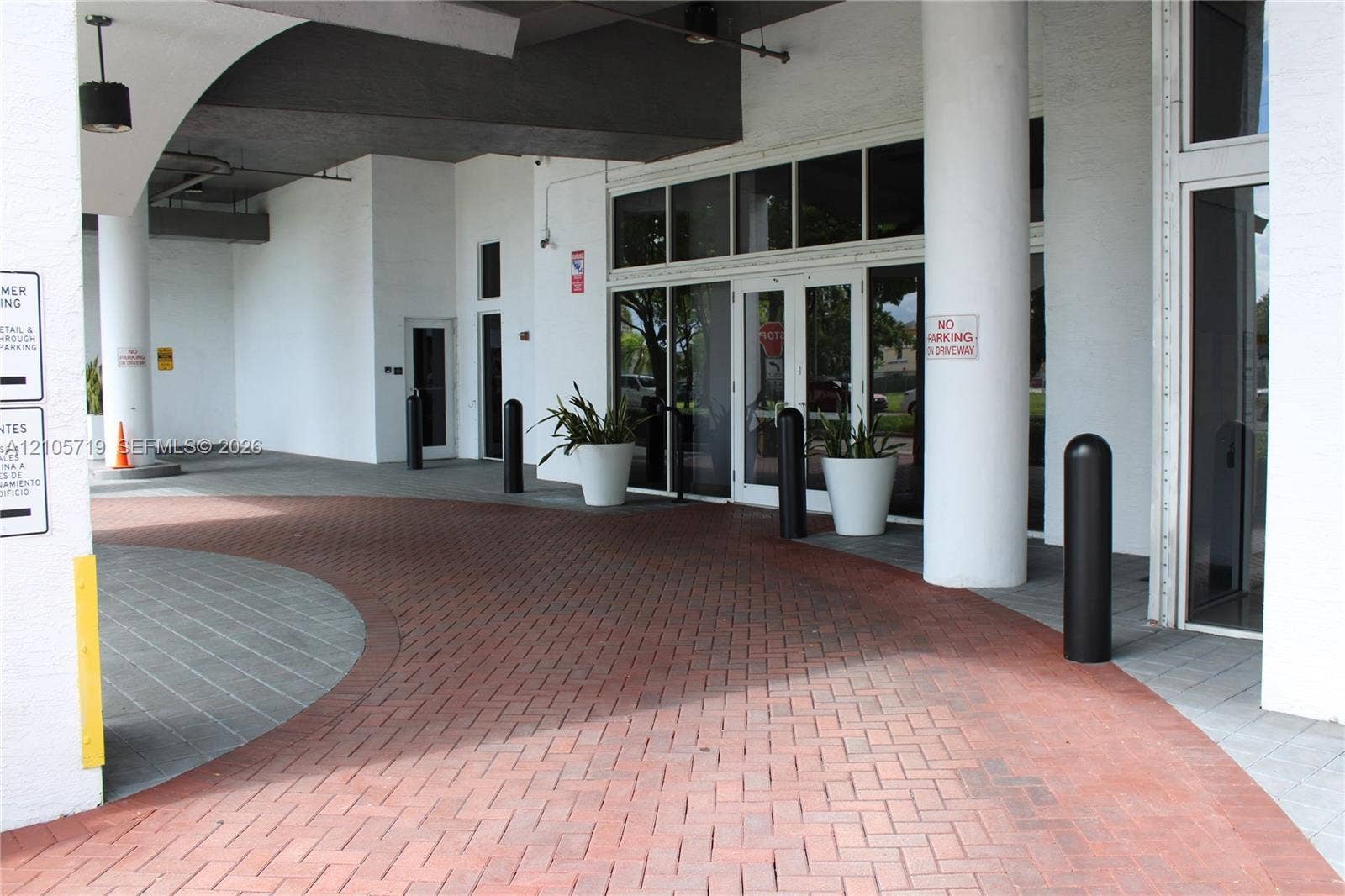 1 Glen Royal Parkway, #1510, Miami, FL 33125 Covered drive-up entrance featuring a herringbone brick paver motor court, structural cylindrical columns, and expansive glass-paneled double entry doors