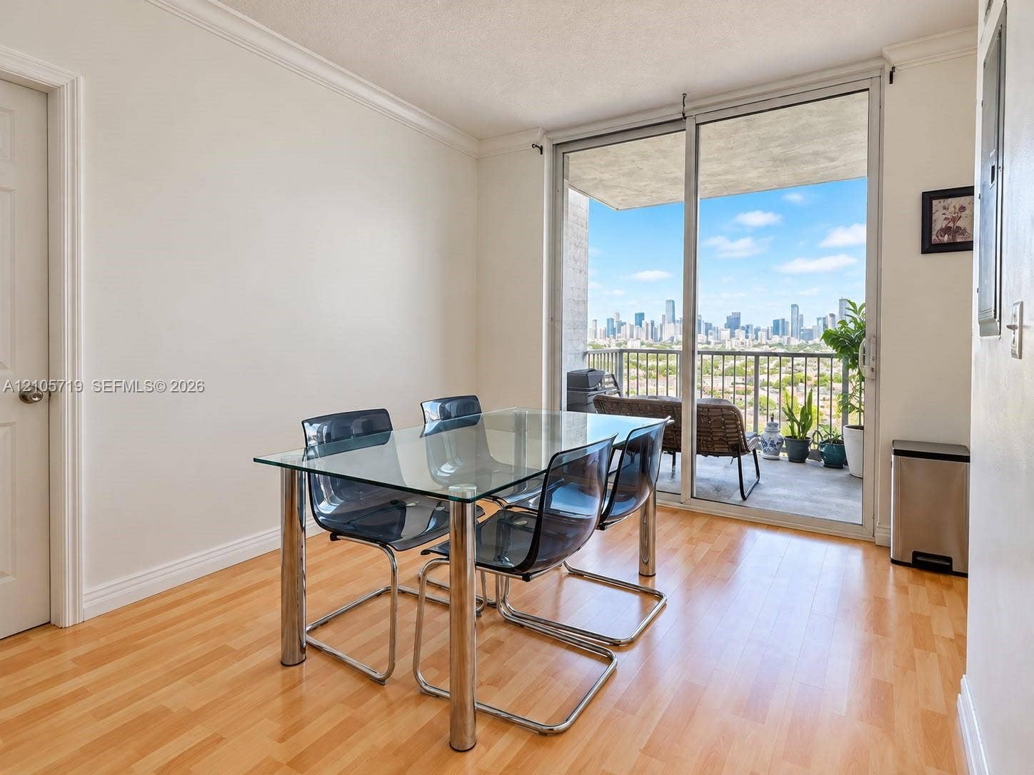 1 Glen Royal Parkway, #1510, Miami, FL 33125 Living area featuring wood-finish flooring, crown molding, and large sliding glass doors leading to a private balcony with cityscape scenery