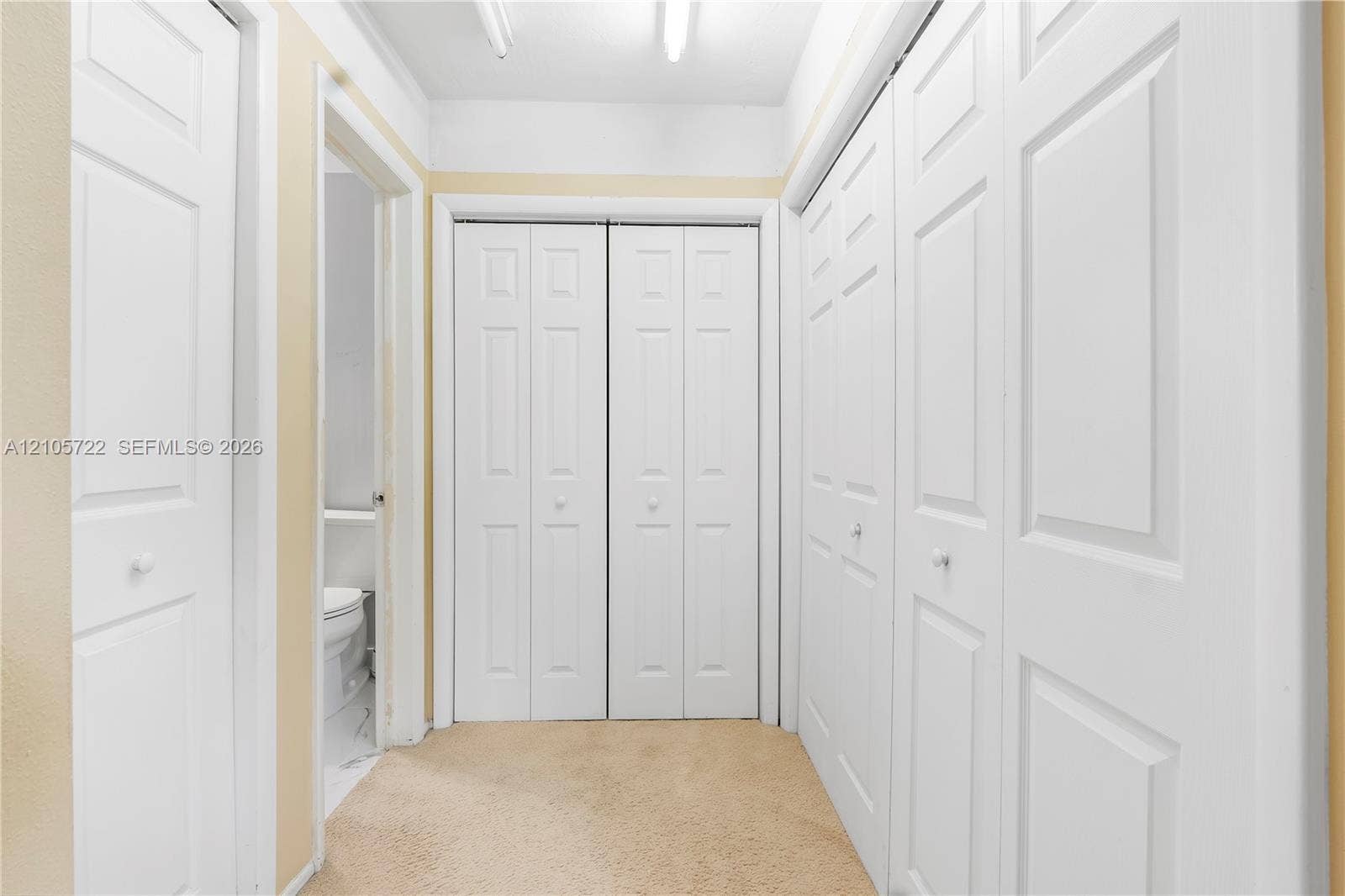 8953 SW 53rd Street, Cooper City, FL 33328 Hallway featuring multiple bi-fold doors, six-panel interior doors, and carpeted flooring