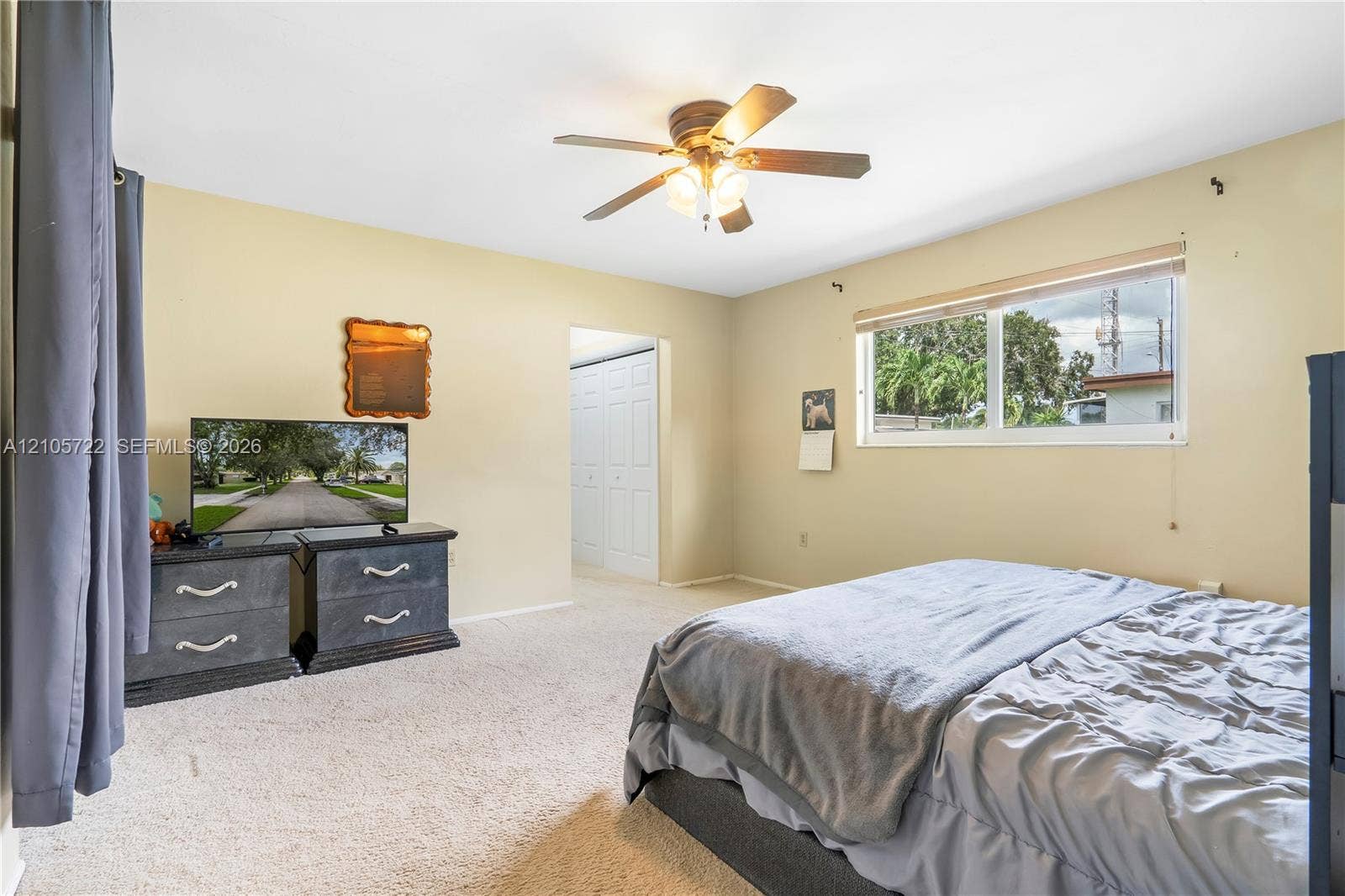 8953 SW 53rd Street, Cooper City, FL 33328 Neutral-toned interior featuring carpeted flooring, a ceiling fan with integrated lighting, and a window with roller shade